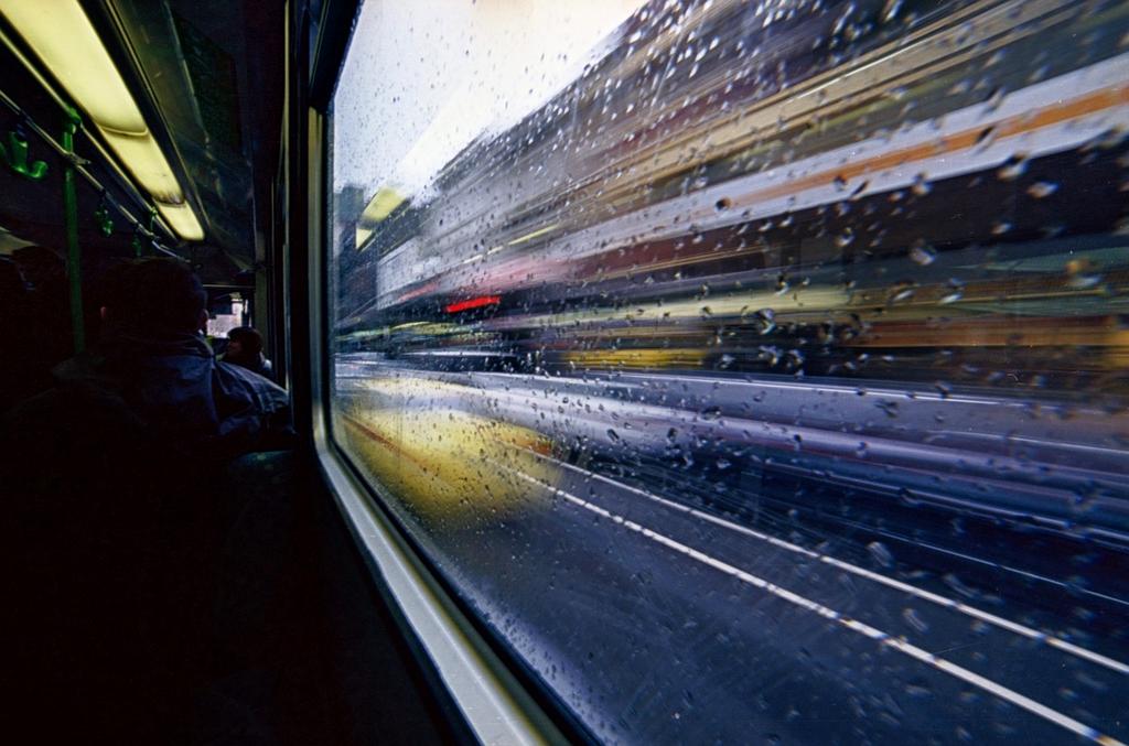 City bus driving along urban street with passengers boarding